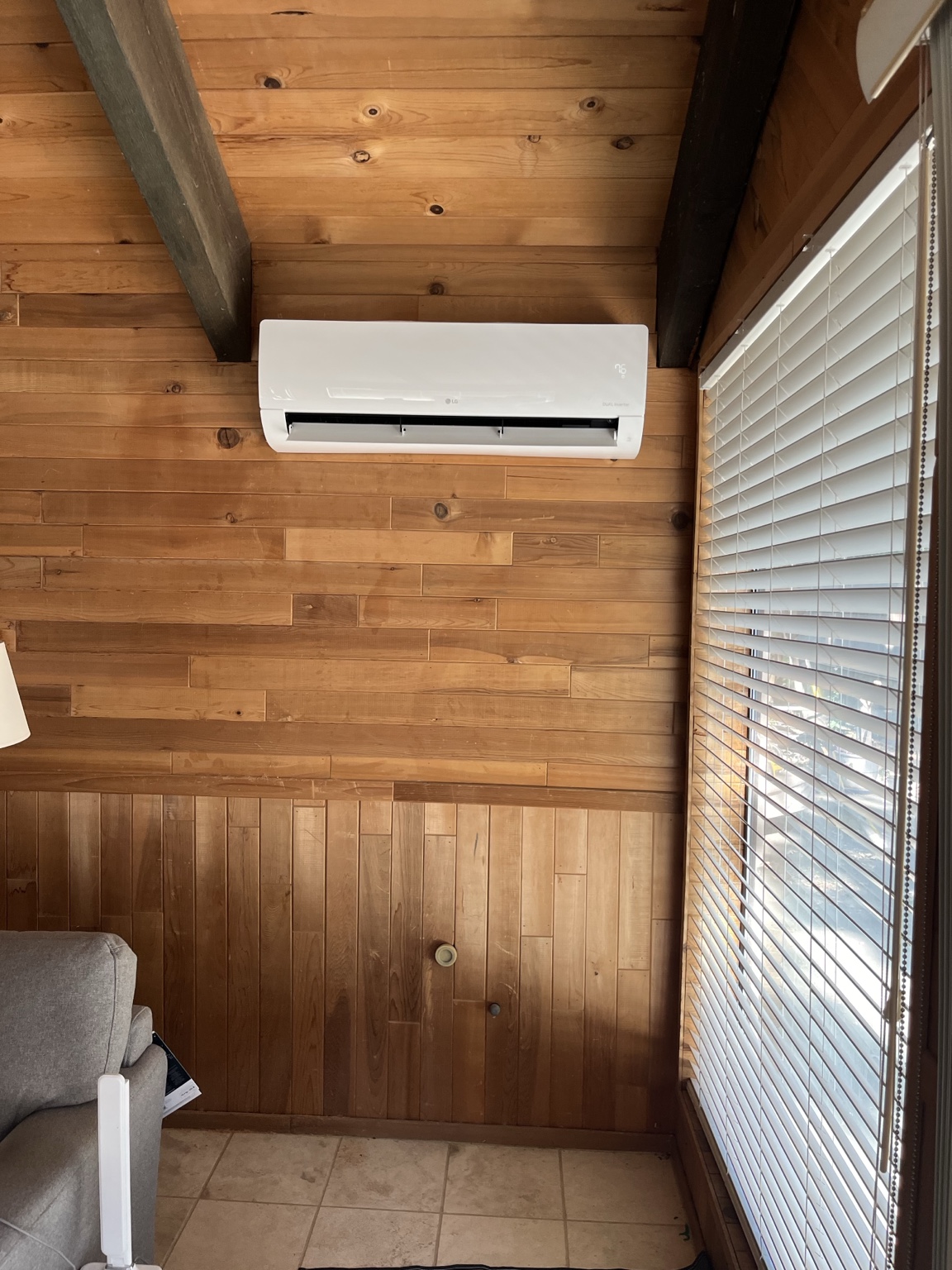 White wall-mounted LG mini-split installed in a wood-paneled room