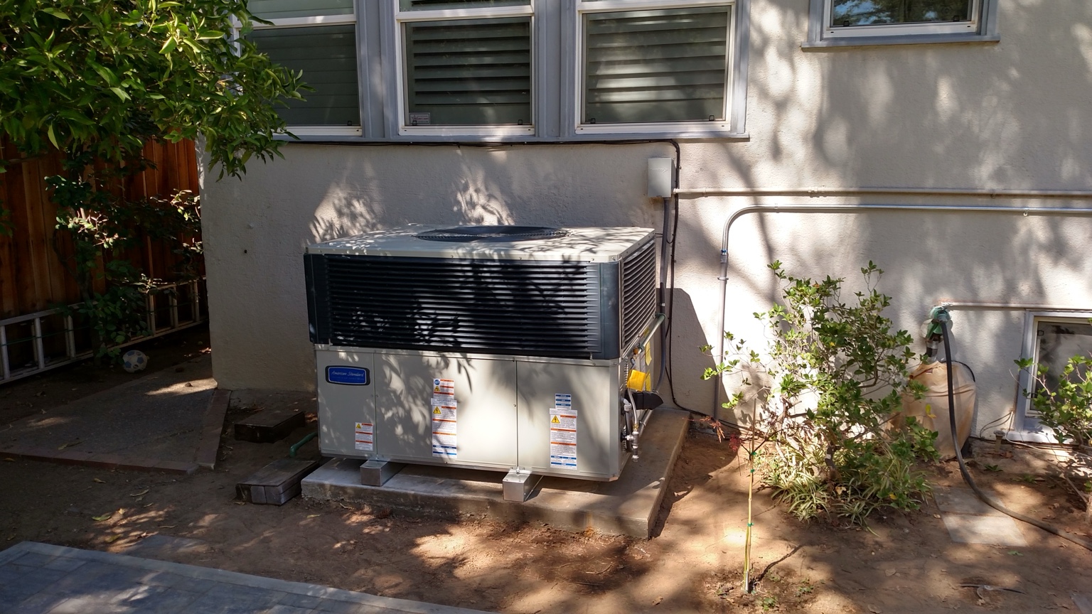 American Standard outdoor heating and cooling system installed beside a home
